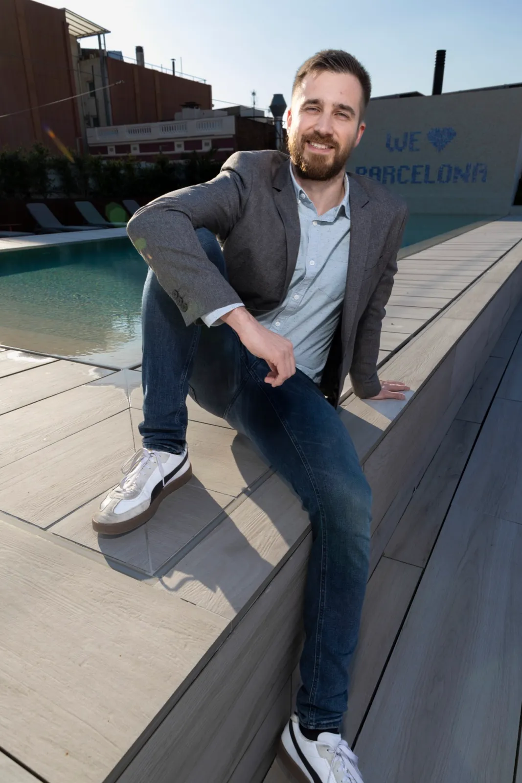 Jakob sitting at the edge of a rooftop pool in front of a We-love-Barcelona mosaic, March 2026.