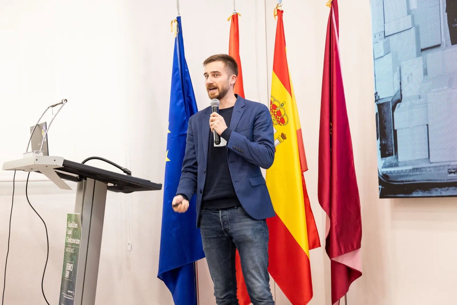 Jakob pitching in front of European and Spanish flags at the Clean Cities ClimAccelerator demo day in Madrid, October 2025.