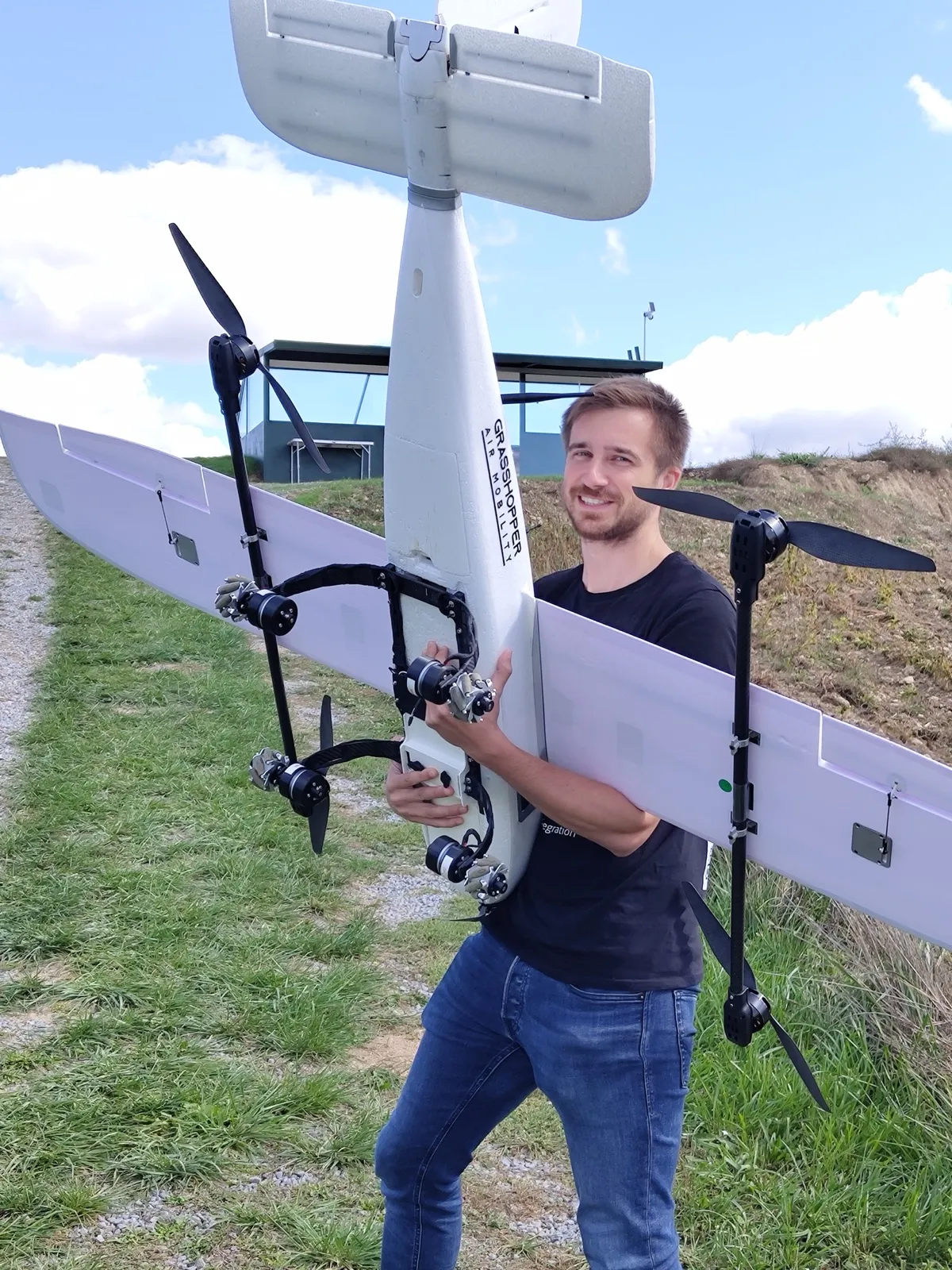 Jakob carrying the Grasshopper proof-of-concept drone across a field on maiden-flight day, September 2025.